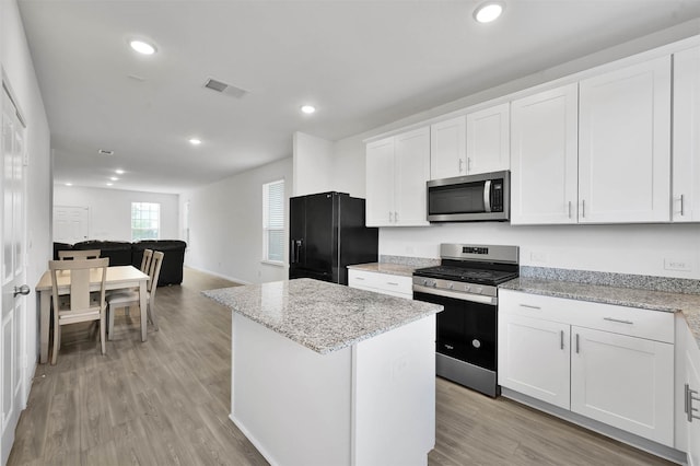 kitchen with white cabinetry, a center island, light stone counters, and appliances with stainless steel finishes