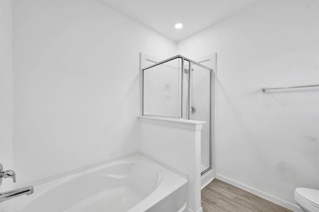 bathroom with hardwood / wood-style floors, separate shower and tub, and toilet