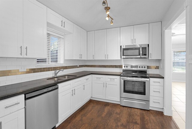 kitchen with sink, dark wood-type flooring, white cabinetry, backsplash, and stainless steel appliances