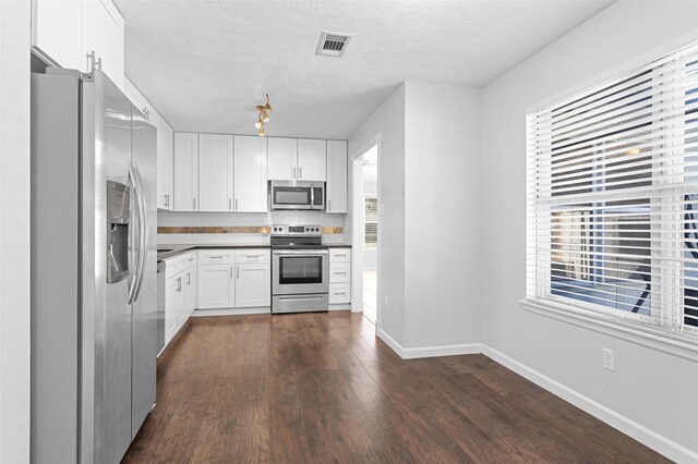 kitchen featuring a healthy amount of sunlight, white cabinetry, appliances with stainless steel finishes, and tasteful backsplash