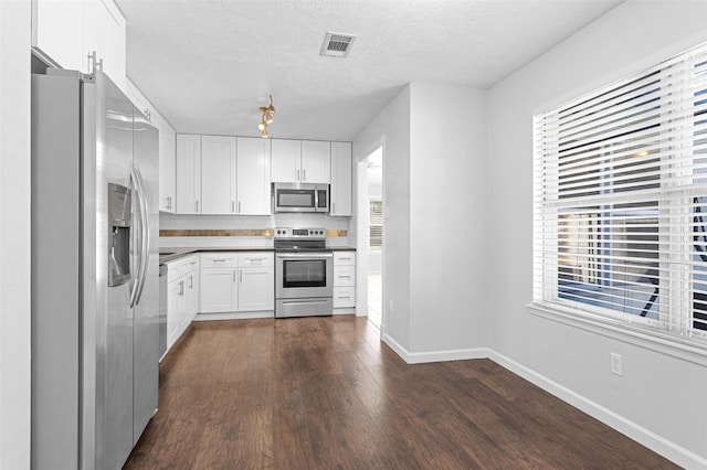 kitchen featuring white cabinetry, stainless steel appliances, a textured ceiling, dark hardwood / wood-style flooring, and decorative backsplash