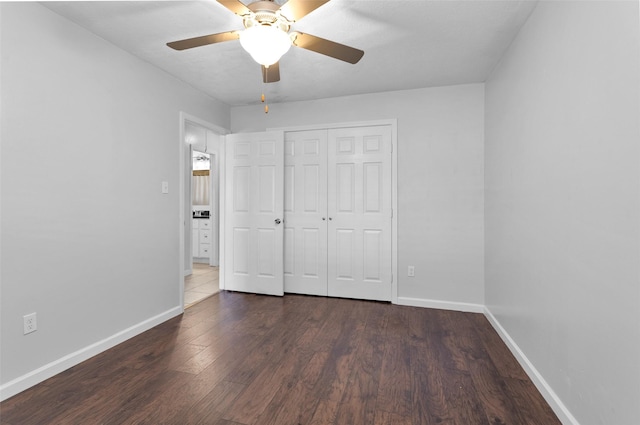 unfurnished bedroom featuring ceiling fan, a closet, and dark wood-type flooring