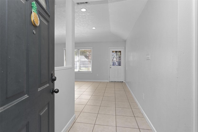 tiled foyer entrance featuring a textured ceiling and vaulted ceiling