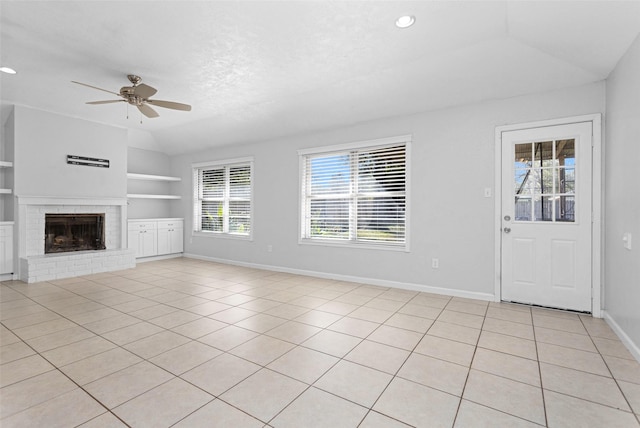 unfurnished living room featuring built in shelves, ceiling fan, lofted ceiling, and light tile patterned floors