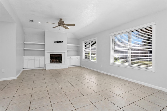 unfurnished living room with light tile patterned floors, ceiling fan, a fireplace, built in shelves, and vaulted ceiling