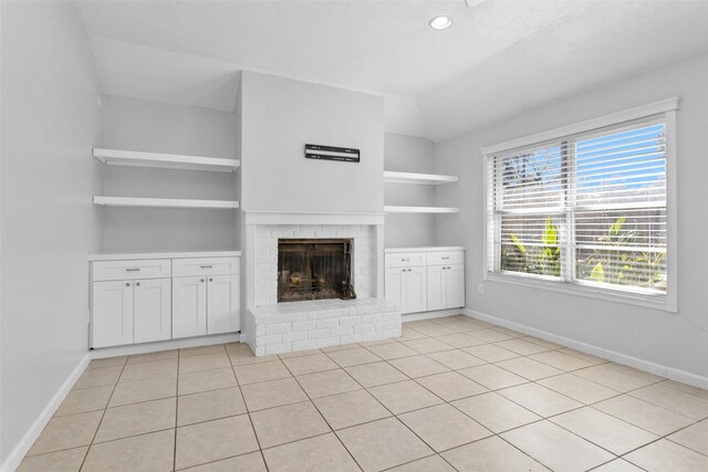 unfurnished living room with a fireplace, light tile patterned floors, and built in features