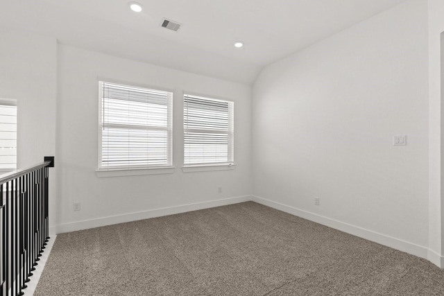 carpeted spare room with vaulted ceiling