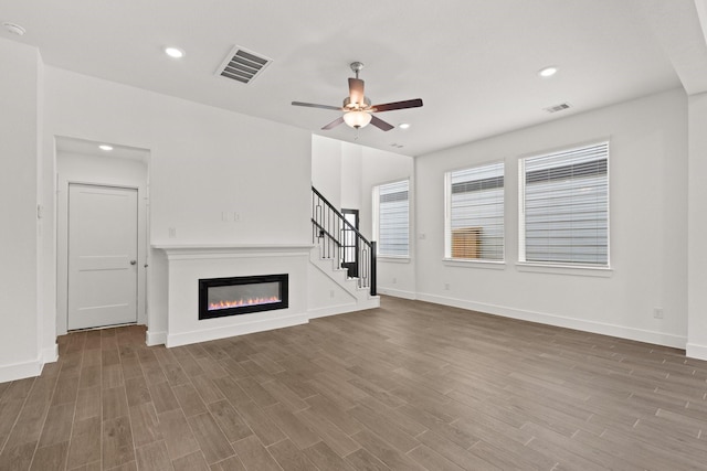 unfurnished living room featuring ceiling fan and dark wood-type flooring