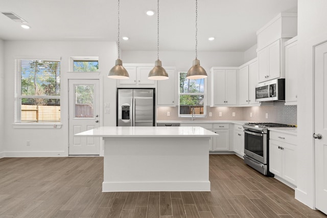 kitchen featuring appliances with stainless steel finishes, pendant lighting, white cabinetry, and a kitchen island