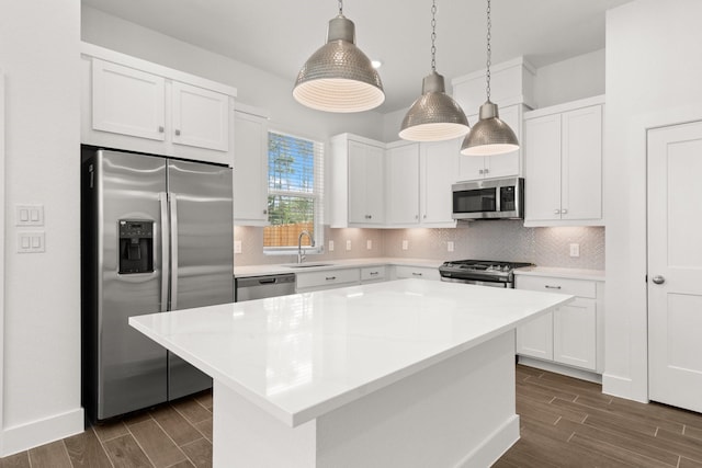 kitchen featuring a center island, stainless steel appliances, white cabinetry, and hanging light fixtures