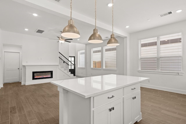 kitchen featuring white cabinets, hanging light fixtures, ceiling fan, beamed ceiling, and a kitchen island