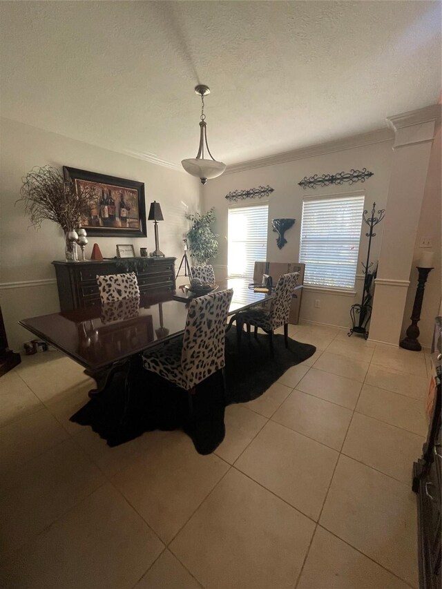 dining area featuring a textured ceiling, light tile patterned floors, and crown molding