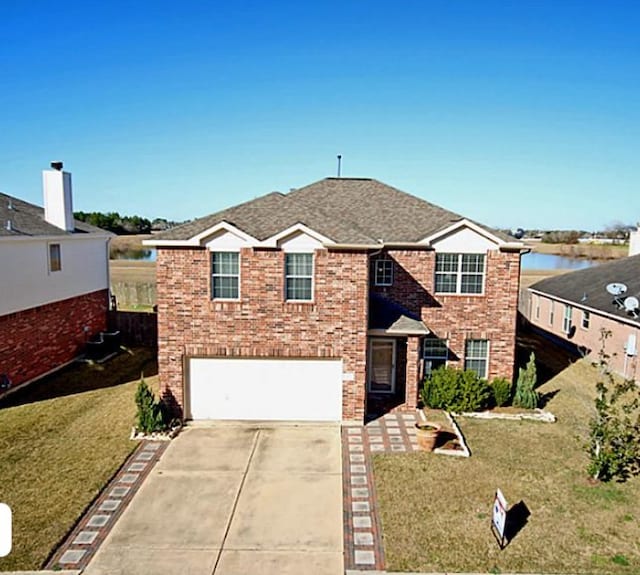 traditional home featuring brick siding, a garage, driveway, and a front yard