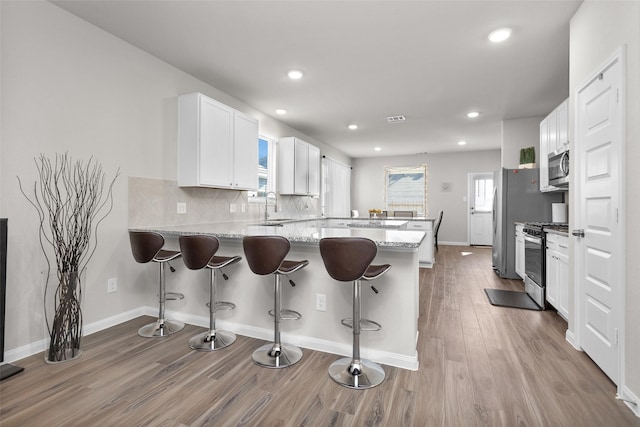 kitchen featuring kitchen peninsula, sink, white cabinets, and appliances with stainless steel finishes