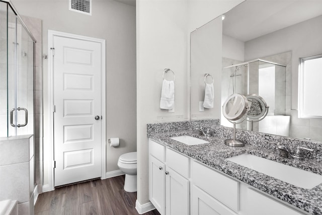 bathroom featuring hardwood / wood-style flooring, vanity, toilet, and a shower with door