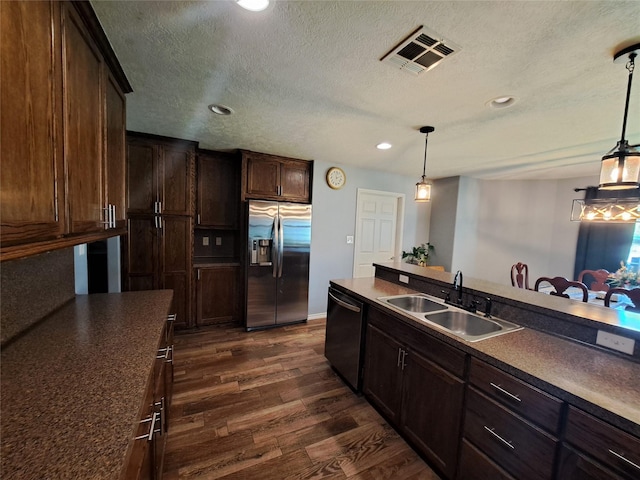 kitchen with appliances with stainless steel finishes, dark brown cabinets, hanging light fixtures, and sink