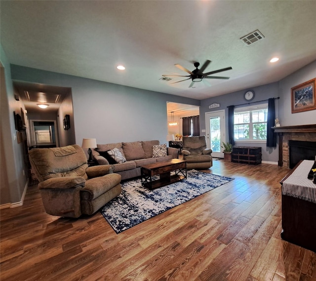 living room featuring a fireplace, wood-type flooring, and ceiling fan