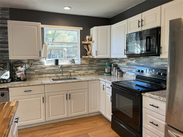 kitchen with black appliances, white cabinets, and sink