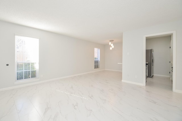 unfurnished room with a textured ceiling and a chandelier