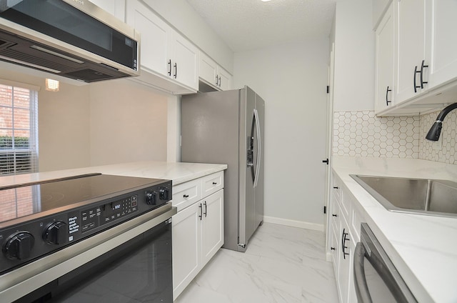 kitchen with stainless steel appliances, sink, white cabinets, a textured ceiling, and light stone countertops