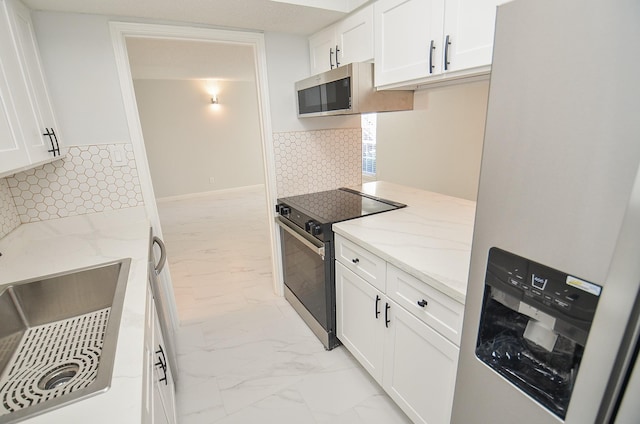 kitchen with stainless steel appliances, white cabinetry, backsplash, and light stone countertops