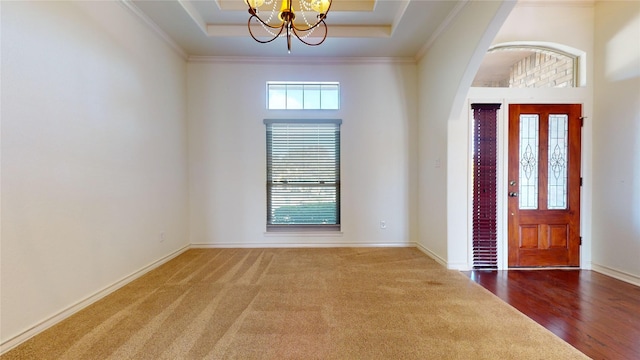 foyer entrance featuring a tray ceiling, a wealth of natural light, and a notable chandelier