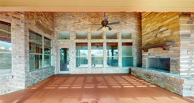 unfurnished living room with a stone fireplace and ceiling fan