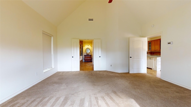 carpeted spare room featuring high vaulted ceiling