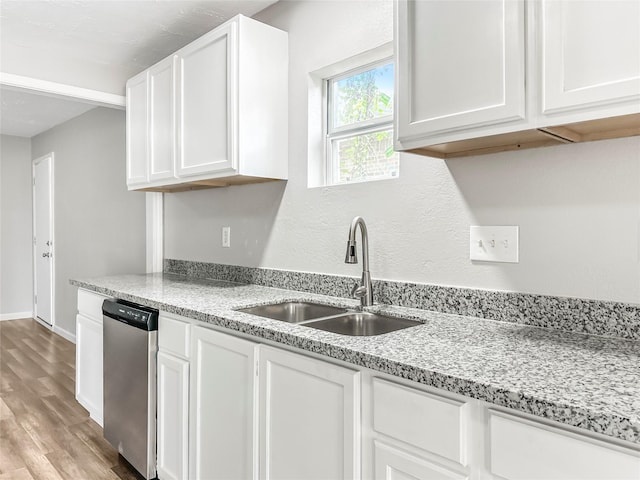 kitchen featuring dishwasher, light stone countertops, white cabinetry, and sink