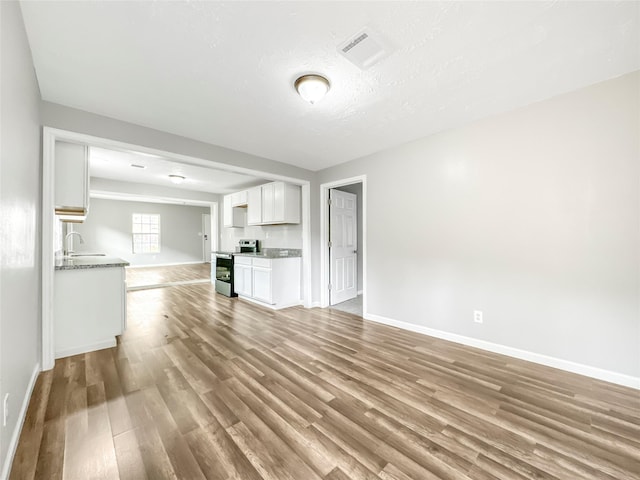 unfurnished living room with sink, a textured ceiling, and hardwood / wood-style flooring