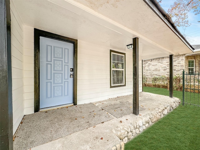 property entrance with a lawn and covered porch