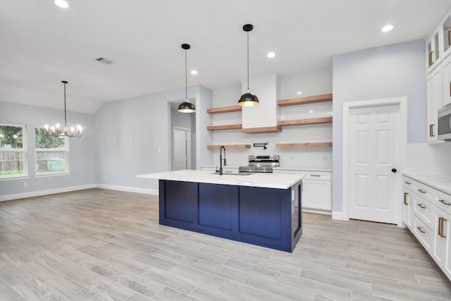 kitchen featuring sink, light stone counters, pendant lighting, a center island with sink, and white cabinets