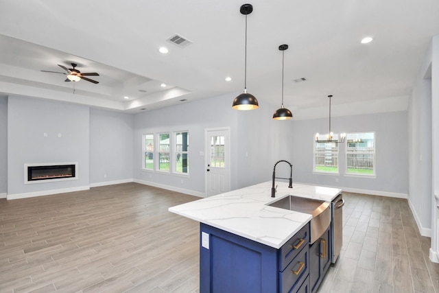 kitchen featuring a tray ceiling, ceiling fan, sink, pendant lighting, and dishwasher