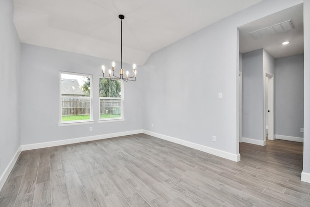 spare room featuring light hardwood / wood-style floors and a chandelier