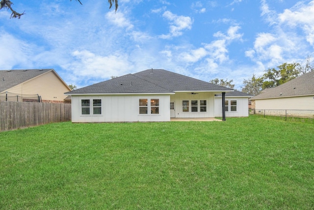 rear view of property featuring ceiling fan, a patio area, and a lawn