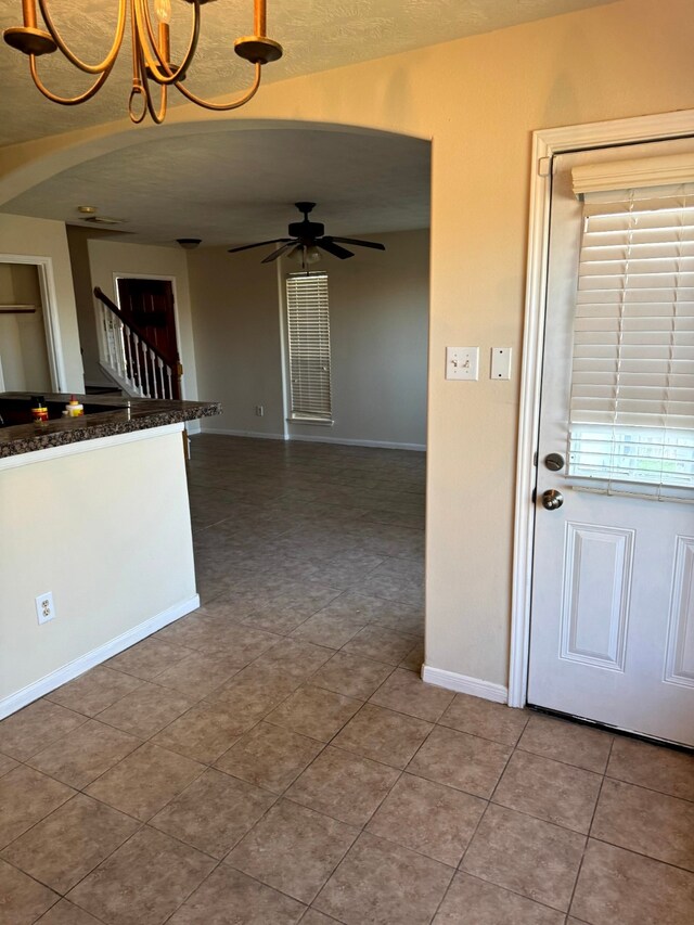 kitchen with tile patterned floors, ceiling fan with notable chandelier, and hanging light fixtures