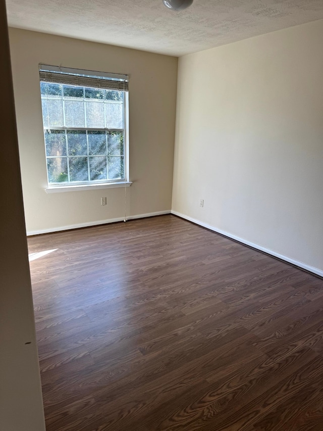 empty room featuring a textured ceiling and dark hardwood / wood-style flooring