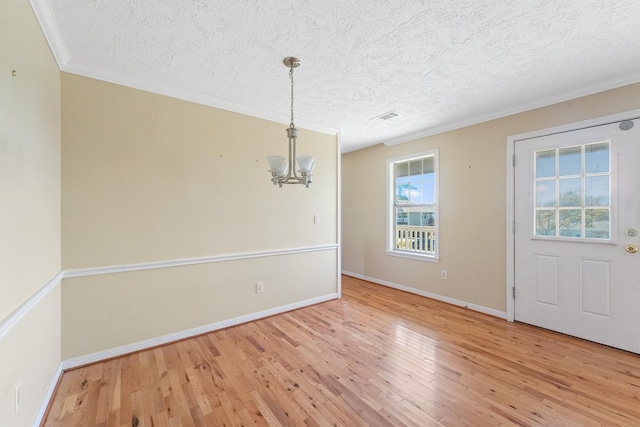 unfurnished dining area with hardwood / wood-style flooring, crown molding, a textured ceiling, and a chandelier