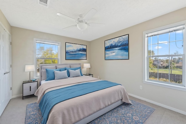 bedroom with a textured ceiling, light colored carpet, and ceiling fan