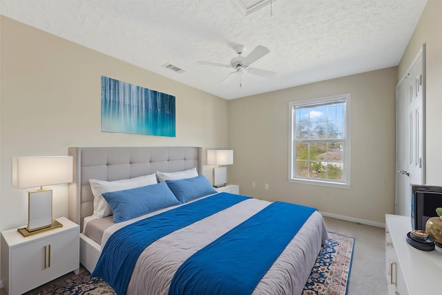 carpeted bedroom with ceiling fan and a textured ceiling