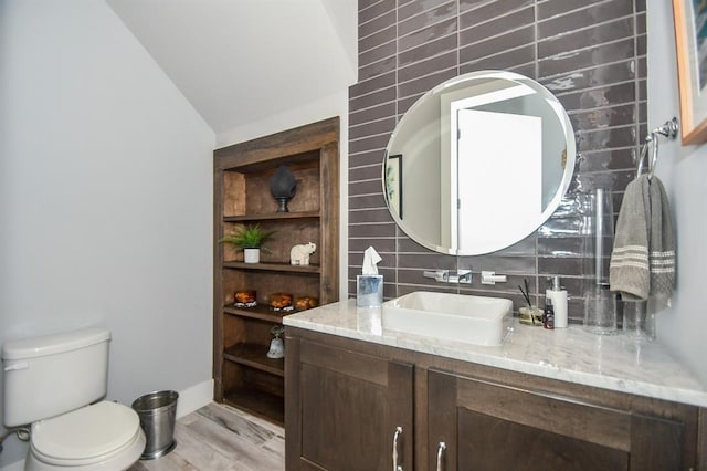 bathroom featuring hardwood / wood-style floors, vaulted ceiling, toilet, tile walls, and tasteful backsplash