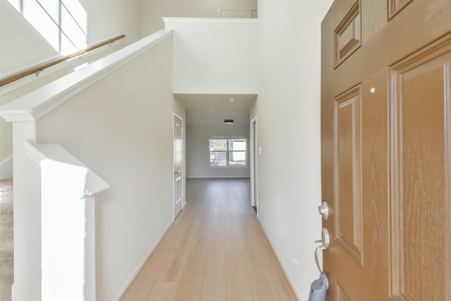 hallway with a towering ceiling and light hardwood / wood-style floors