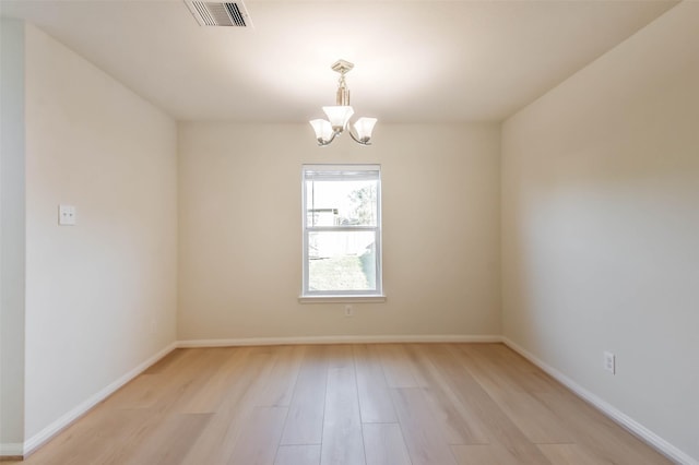 empty room featuring light hardwood / wood-style floors and a chandelier