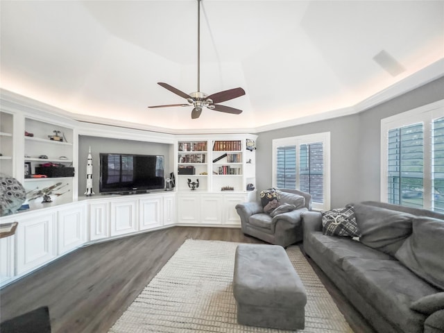 living room featuring a tray ceiling, ceiling fan, dark hardwood / wood-style flooring, and built in features