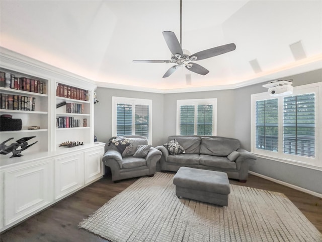 living room with ceiling fan, a raised ceiling, and dark wood-type flooring