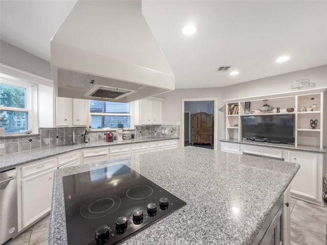 kitchen featuring a center island, backsplash, island range hood, black electric stovetop, and white cabinets