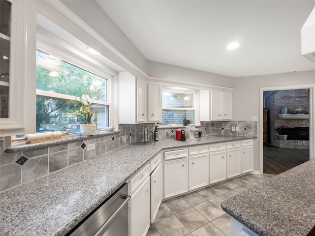 kitchen featuring stone counters, white cabinetry, tasteful backsplash, stainless steel dishwasher, and light tile patterned flooring