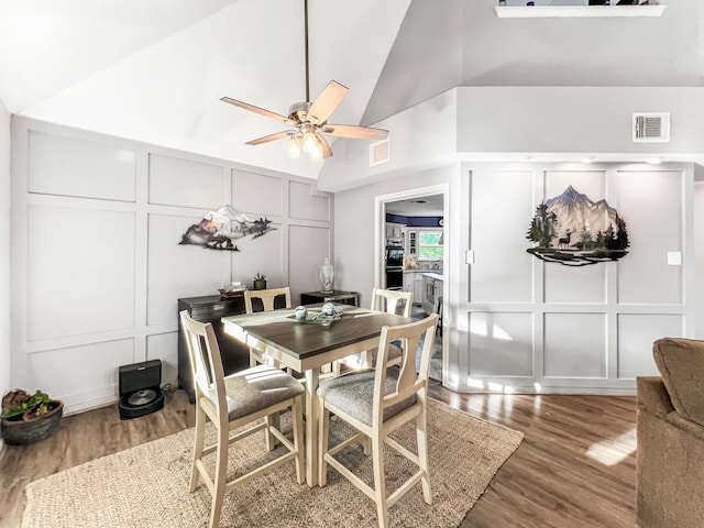 dining space featuring dark hardwood / wood-style floors, high vaulted ceiling, and ceiling fan