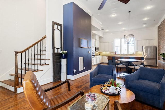 living room featuring ceiling fan with notable chandelier, dark hardwood / wood-style floors, and ornamental molding