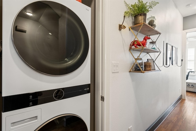 laundry room with stacked washing maching and dryer and dark hardwood / wood-style floors